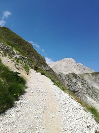 Man walking on mountain against clear blue sky