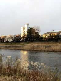 River by buildings against sky