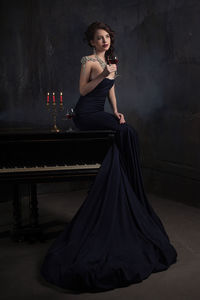 Beautiful woman in gown having red wine at home