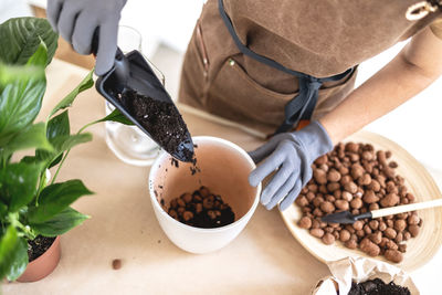 Cropped hand of woman holding coffee beans on table