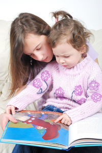 Sisters looking at book at home