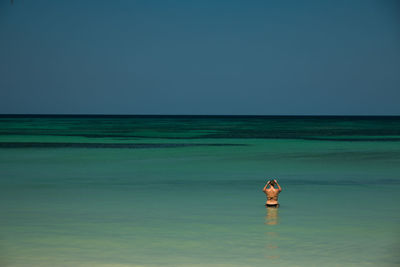 Woman standing in sea against clear sky