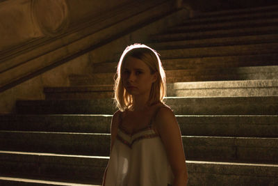 Full length of young woman sitting on steps at night