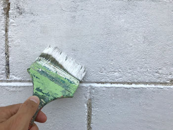 Close-up of hand holding ice cream against wall