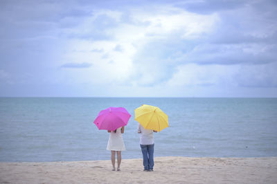 Rear view of women on beach against sky