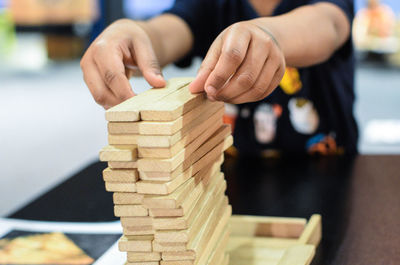 Cropped image of man stacking dominoes on table
