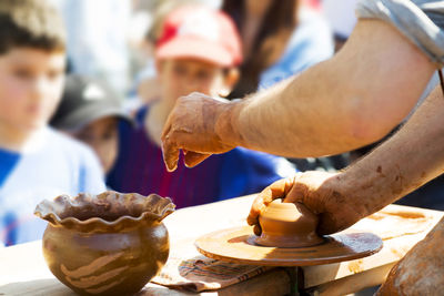 Midsection of potter making bowl in market