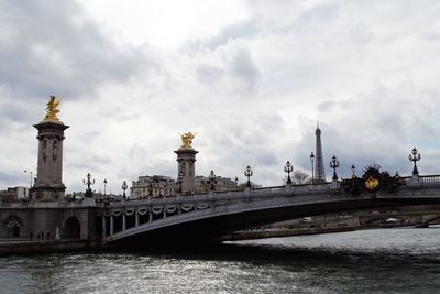 Bridge over river against cloudy sky