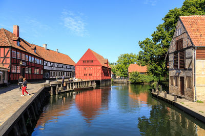 Canal amidst buildings against blue sky