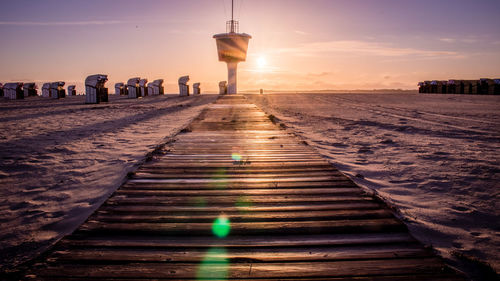 People on illuminated walkway against sky during sunset