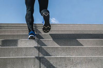 Young man exercising climbs stairs outdoors. cut the view of strong and powerful legs 