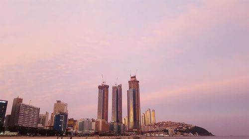 Modern buildings in city against sky during sunset