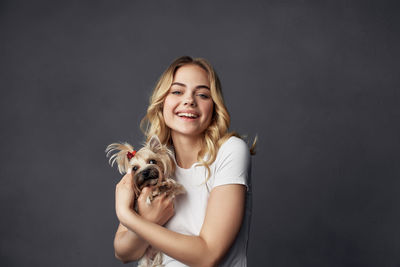 Portrait of woman with dog against gray background