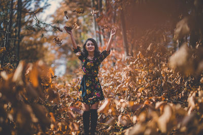 Portrait of young woman standing by plants