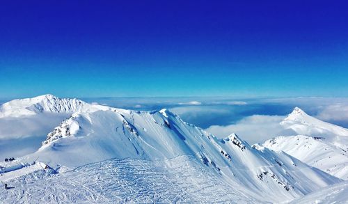 Scenic view of snowcapped mountains against blue sky