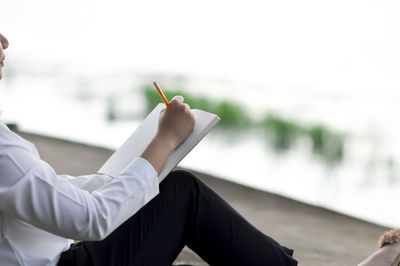 Midsection of man holding paper against blurred background
