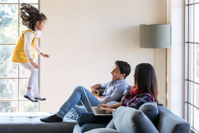 Rear view of friends sitting on sofa at home