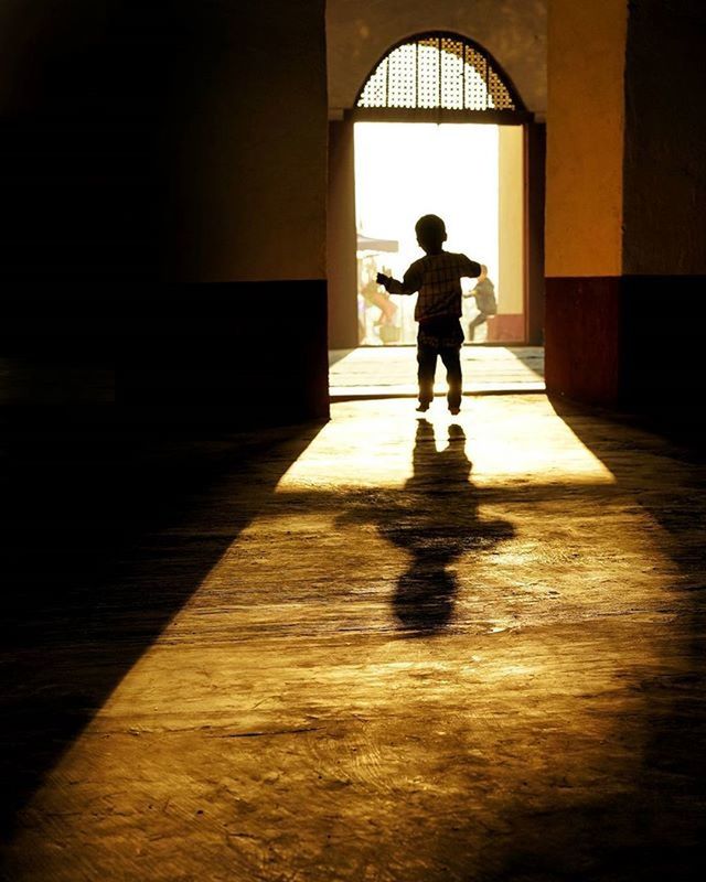 indoors, full length, architecture, built structure, lifestyles, silhouette, walking, corridor, rear view, flooring, standing, leisure activity, men, door, window, sunlight, shadow, person