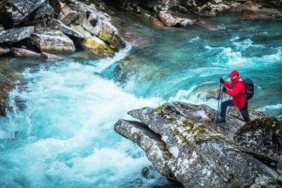 High angle view of hiker standing on rock over river