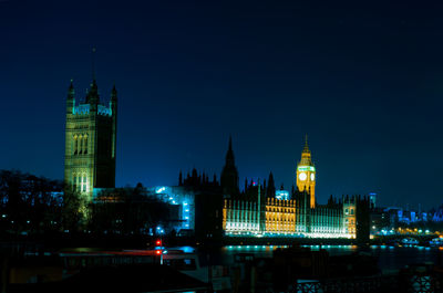 Illuminated buildings in city against clear sky at night