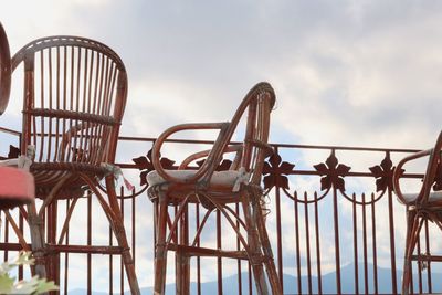 Chairs by railing against sky