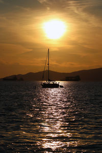 Silhouette sailboat sailing on sea against sky during sunset