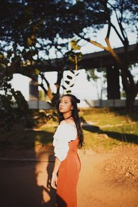 Portrait of woman standing by tree