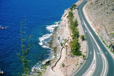 High angle view of road by sea against blue sky