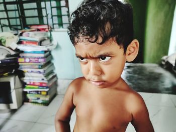 Close-up of shirtless boy looking away standing at home