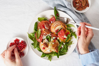 Woman eating fruits citrus salad with nuts, green lettuce leaves. balanced food. top view 