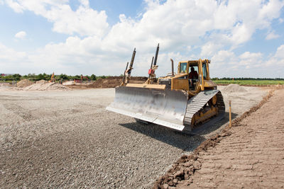 Man driving bulldozer at construction site against sky