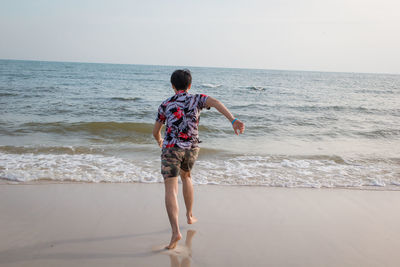 Rear view of man on beach against sky