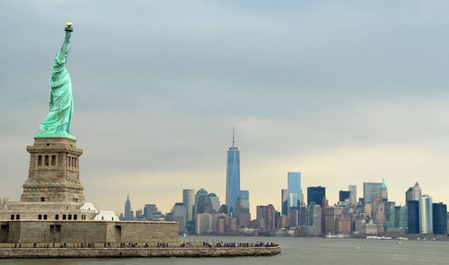 Statue of liberty in city against sky during sunset