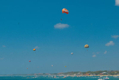 Scenic view of sea against blue sky with some of paragliders in bali