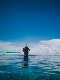 Man in sea against blue sky