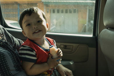 Midsection of mother carrying baby boy on lap while sitting in car