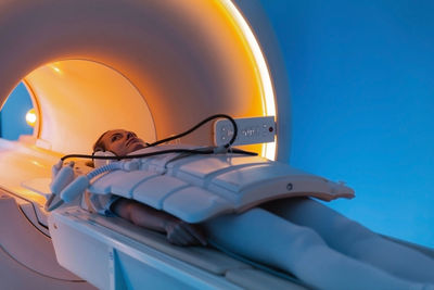 Rear view of woman relaxing on bed against blue sky