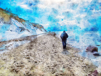 Rear view of man standing on sea shore against sky