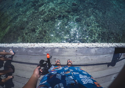 Low section of woman with scuba mask standing on pier over lake