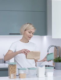 Portrait of female friends washing hands in kitchen