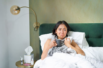 Portrait of young woman sitting on bed at home