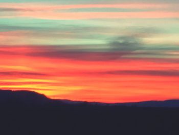 Scenic view of silhouette mountains against orange sky