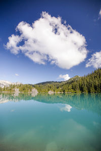 View of alpine lake and reflection of mountains and forest.