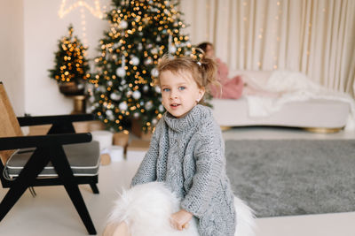 Portrait of cute girl with christmas tree at home