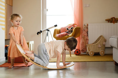 Children playing on balance board for toddlers in kids room. curvy rocker board used for motor