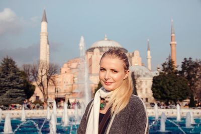 Portrait of young woman against the sky in city