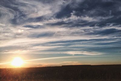 Scenic view of silhouette field against sky at sunset