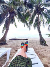 Man relaxing at beach against sky