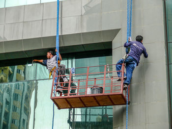 Low angle view of people working on building