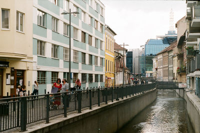 Canal amidst buildings in city against sky